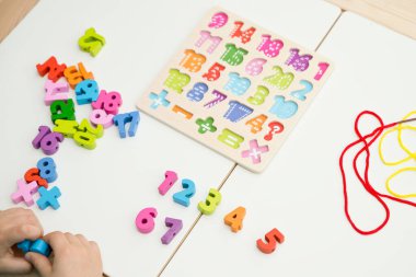 Çocuk oyun yoluyla numaraları öğreniyor. Tahta sayılar ve ayakkabı bağcıklarıyla duyusal aktivite. Evde eğitim, okul öncesi eğitim, Montessori metodolojisi. sayılar dizisi, aritmetik problemler.