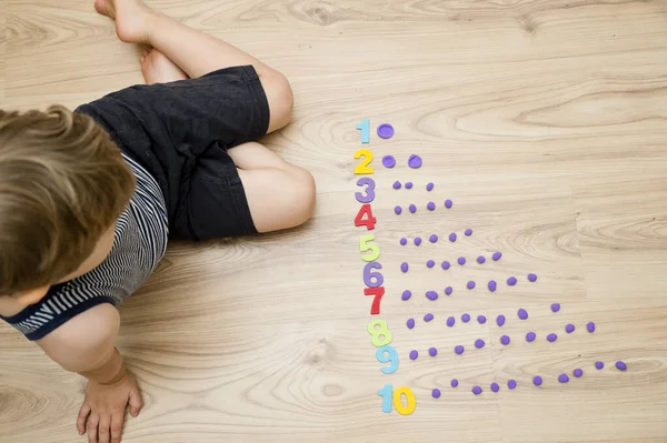 Play-Doh taşları ve numaraları. DIY oyunu sayılıyor. Matematiksel bir görev. Evde oyna. Öğrenmenin bir yolu. Çocuk bir rakam söylerken topları düzleştirdi.