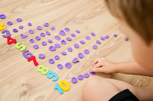 Play-Doh stones and numbers. Counting DIY game. Mathematical task. Play at home. Way of learning. Kid flatten balls when saying a digit.
