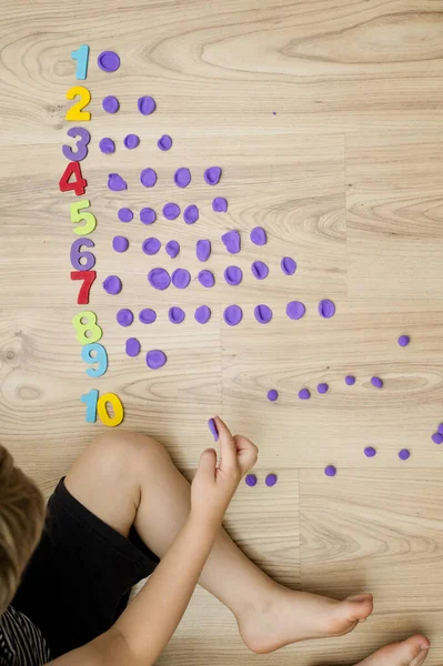 Play-Doh taşları ve numaraları. DIY oyunu sayılıyor. Matematiksel bir görev. Evde oyna. Öğrenmenin bir yolu. Çocuk bir rakam söylerken topları düzleştirdi.