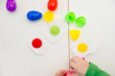 Mutlu Paskalyalar teması. Yumurta sıralayan ve renkleri öğrenen çocuk. Çocuk eğitimi için Montessori formatı görevi. İyi motor becerileri ve hayal gücü eğitimi için okul öncesi oyuncağı..