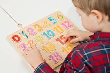 Çocuk oyun yoluyla numaraları öğreniyor. Ahşap sayılarla etkinlik. Evde eğitim, okul öncesi eğitim, Montessori metodolojisi. Saymayı öğrenmek ve hayal gücünü ve yaratıcılığı canlandırmak için.