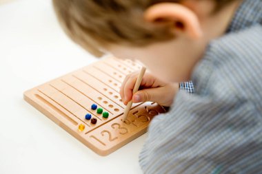 Montessori Boncuklar Kurulu. Sayıları saymayı ve yazmayı öğrenmek, çocuğu zihinsel aritmetiğe hazırlamak, bir düzen, odaklanma, koordinasyon ve doğruluk duygusu geliştirmek.