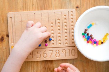 Montessori Boncuklar Kurulu. Sayıları saymayı ve yazmayı öğrenmek, çocuğu zihinsel aritmetiğe hazırlamak, bir düzen, odaklanma, koordinasyon ve doğruluk duygusu geliştirmek.
