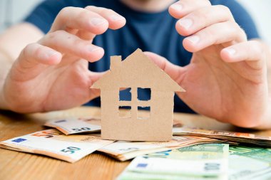 Hayalimdeki ev için para biriktiriyorum. Bir elinde kart tutan bir adam. Yeni ev teması için kredi. Kredi, borç, mali işlemler. Akıllı yatırım.