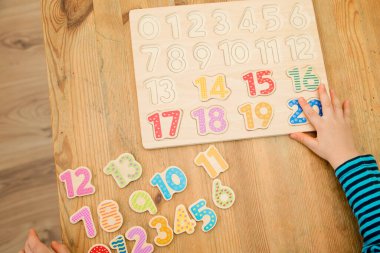Çocuk oyun yoluyla numaraları öğreniyor. Ahşap sayılarla etkinlik. Evde eğitim, okul öncesi eğitim, Montessori metodolojisi. Saymayı öğrenmek ve hayal gücünü ve yaratıcılığı canlandırmak için.