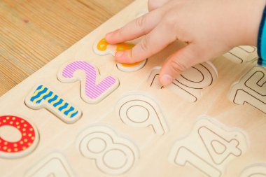 Çocuk oyun yoluyla numaraları öğreniyor. Ahşap sayılarla etkinlik. Evde eğitim, okul öncesi eğitim, Montessori metodolojisi. Saymayı öğrenmek ve hayal gücünü ve yaratıcılığı canlandırmak için.