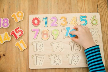 Çocuk oyun yoluyla numaraları öğreniyor. Ahşap sayılarla etkinlik. Evde eğitim, okul öncesi eğitim, Montessori metodolojisi. Saymayı öğrenmek ve hayal gücünü ve yaratıcılığı canlandırmak için.