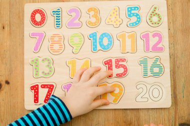 Çocuk oyun yoluyla numaraları öğreniyor. Ahşap sayılarla etkinlik. Evde eğitim, okul öncesi eğitim, Montessori metodolojisi. Saymayı öğrenmek ve hayal gücünü ve yaratıcılığı canlandırmak için.