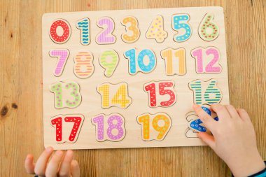 Çocuk oyun yoluyla numaraları öğreniyor. Ahşap sayılarla etkinlik. Evde eğitim, okul öncesi eğitim, Montessori metodolojisi. Saymayı öğrenmek ve hayal gücünü ve yaratıcılığı canlandırmak için.