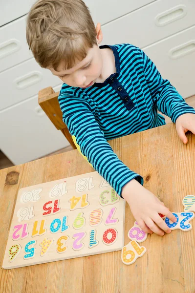 Çocuk oyun yoluyla numaraları öğreniyor. Ahşap sayılarla etkinlik. Evde eğitim, okul öncesi eğitim, Montessori metodolojisi. Saymayı öğrenmek ve hayal gücünü ve yaratıcılığı canlandırmak için.