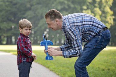 Oğlan, uçağı ağaca sıkıştığında ağlar. Adam çocuğu rahatlatır, sakinleşmesine ve mavi oyuncağı geri vermesine yardım eder. Babalar ve oğullar, aile bağları. Açık hava aktiviteleri. Aileyle hafta sonu.