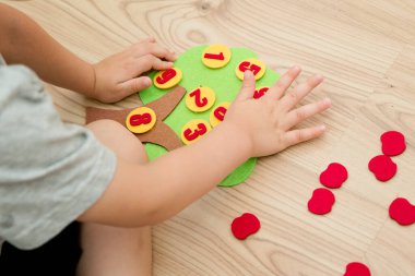 Elma ağacını numaralarla hissettim. Çocukların saymayı öğrenmesi için anaokulu uygulaması. Montessori konsepti, erken eğitim. Çocuklar el üstünde oyuncak.