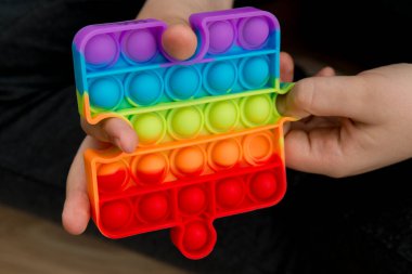 Çocuk popüler bir oyuncak tutuyor, patlatıyor. Parmaklarının iyi motor becerilerini geliştirmek için kullanışlı oyuncaklar. Stres önleyici oyuncak. Çocuklar için eğlenceli oyunlar. otizm Bilinci Günü.