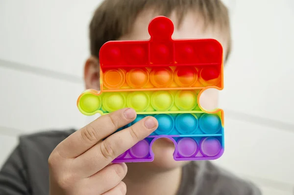 Child holds a popular toy pop it. Useful toys for the development of fine motor skills of the fingers. Anti-stress toy. entertaining games for children. awareness autism day.