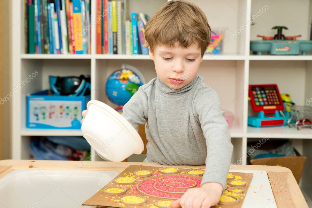 El chico juega con arroz de colores. Implementar para que los niños