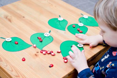 Uğur böceğinin miktarını belirlenmiş ağaç yaprağına yaz. Bebek sayma oyunu oynuyor. Anaokulları için anaokulu eğitimi yardımı. Çocuklar zeka ve gelişim için montessori setini erken öğreniyor