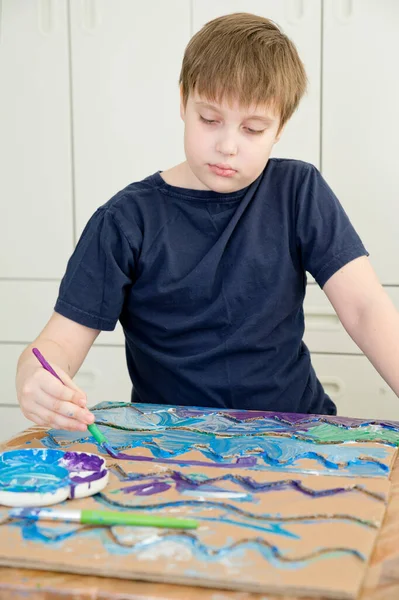 Zero waste. Corrugated cardboard cut and glued to make terrain. boy painting it to look like sea. DIY games at home. save the ocean concept.