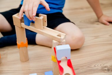 Cascading marble run. Children play with wooden track and balls. A fun playful game. Creativity and construction design. Montessori methodology for kindergarten and preschool children.