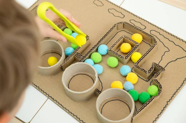 Pompom train. 3D train board for active brain exercise game made from paper core tubes and cardboard. Montessori methodology task to sort different colors.