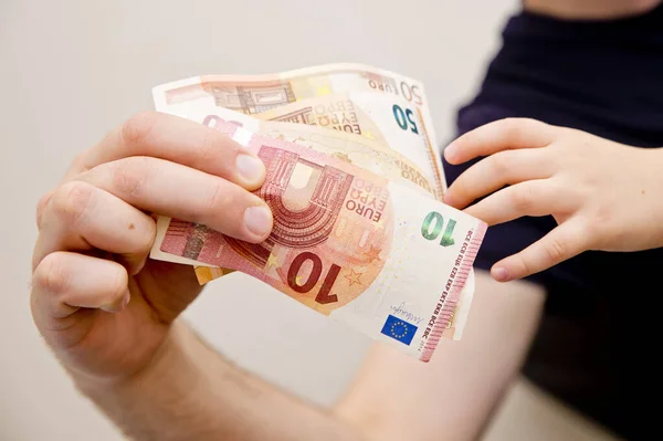 Mans and kids hands on Euro banknotes. Investment, children's life insurance, savings for children's education.