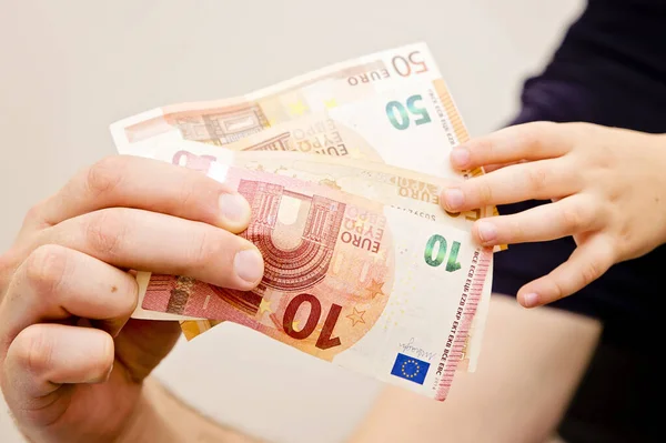 Mans and kids hands on Euro banknotes. Investment, children's life insurance, savings for children's education.