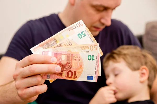 Mans and kids hands on Euro banknotes. Investment, children\'s life insurance, savings for children\'s education.