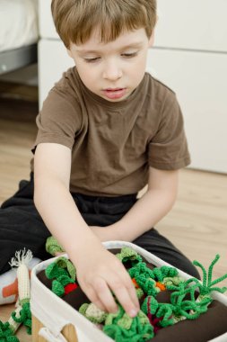 Çocuk bir bahçıvan oyunu oynuyor. Tarlaları hasat et. Çocuklar için sağlıklı yiyecekler. Bahçıvanlık ve tarım kavramı. Evdeki etkinlikler. Doğanın bilgisi. El yapımı oyuncaklar, sebzeler..