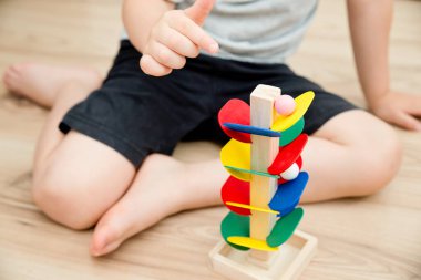 Tahta mermer yarış kulesi. Çocuklar oyun oynamak için oyun oynarlar. Çocuk topu başlangıç pozisyonuna getiriyor. Evdeki etkinlikler. Tablo ve zemin oyunu.