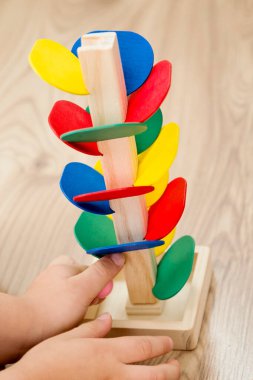 Tahta mermer yarış kulesi. Çocuklar oyun oynamak için oyun oynarlar. Çocuk topu başlangıç pozisyonuna getiriyor. Evdeki etkinlikler. Tablo ve zemin oyunu.