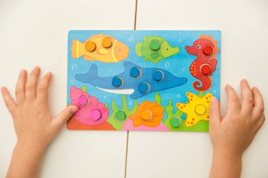 Match the color. Wooden table game with colored cylinders. Toy for Toddlers. For verbal and visual learning.