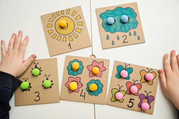 Hand made children home activity from cardboard and pom poms. Early education, Montessori methodology. Implement to develop fine motoric skills, logical thinking learn counting.