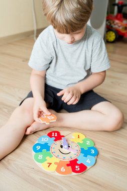 Çocuk, tahta saatle vakit geçirmeyi öğreniyor. Çocuk Eğitimi için Öğrenme Metodu. Anaokulu ya da özel görevler. Montessori yöntembilimi.