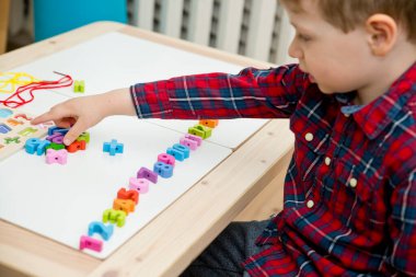 Çocuk oyun yoluyla numaraları öğreniyor. Tahta sayılar ve ayakkabı bağcıklarıyla duyusal aktivite. Evde eğitim, okul öncesi eğitim, Montessori metodolojisi. sayılar dizisi, aritmetik problemler.