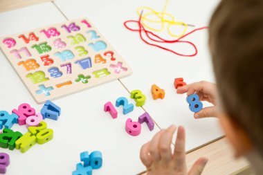 Çocuk oyun yoluyla numaraları öğreniyor. Tahta sayılar ve ayakkabı bağcıklarıyla duyusal aktivite. Evde eğitim, okul öncesi eğitim, Montessori metodolojisi. sayılar dizisi, aritmetik problemler.