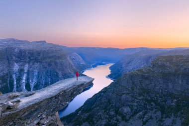 Alone tourist on Trolltunga rock - most spectacular and famous scenic cliff in Norway - Landscape clipart