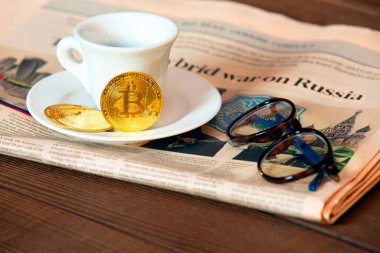 New York, New York, ABD, Mart 06. 2022: Sabah bitcoin kripto-para birimi, bir fincan lezzetli kahve ve gazete Rus askeri güçleri tarafından Ukrayna 'nın önceki gece işgali hakkında rapor verdi.