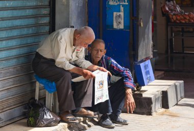 Jordan, Amman - 25-04-2022: Yolun kenarında gazete okuyan iki adam.