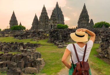 Günbatımında Prambanan Tapınağı 'nın simgesini arayan bir kadın turist. Beyaz elbiseli ve şapkalı Asyalı kadın..