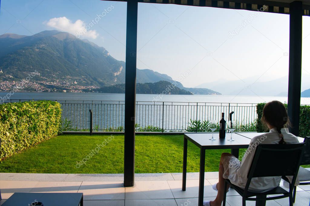 Young woman drinking coffee while looking at Stunning Sunrise on Lake Como Italy  Vacation concept