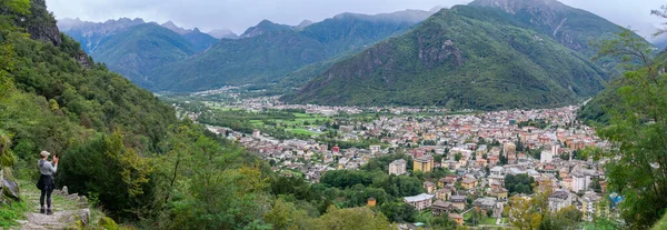 İtalyan Alplerinde küçük bir Avrupa kasabası olan Prosto Italya 'nın panoramasının telefonuyla fotoğraf çeken kadın turist