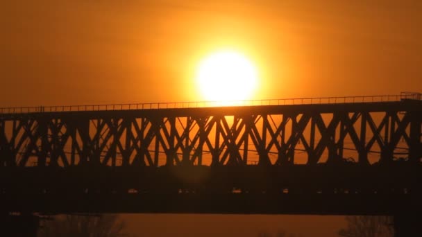 Trainen op de brug bij zonsondergang. spoorweg. — Stockvideo