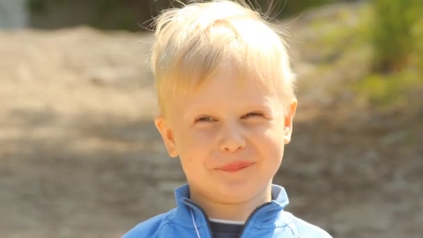 Pozytywne blond chłopiec uśmiecha na zewnątrz — Wideo stockowe