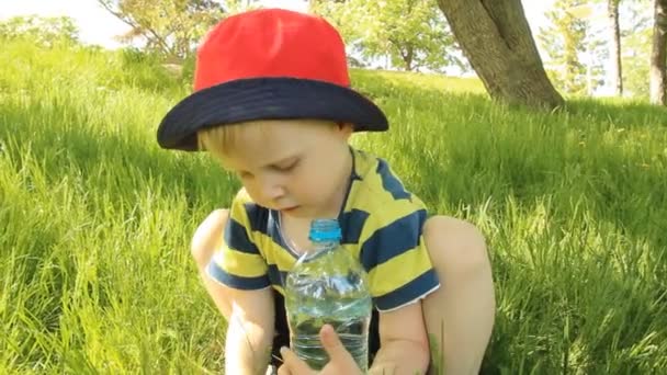 Kleine jongen op de weide drinkwater — Stockvideo