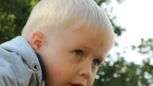 Маленький мальчик стоит у металлического забора — стоковое видео