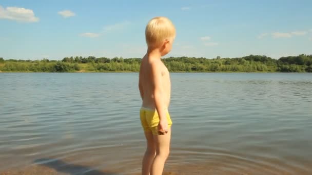 Mały chłopiec bawi się na brzegu jeziora. rekreacji wodnej — Wideo stockowe