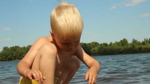 Kleine jongen spelen op de oever van het meer. Waterrecreatie — Stockvideo