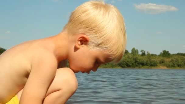 Kleine jongen spelen op de oever van het meer. Waterrecreatie — Stockvideo