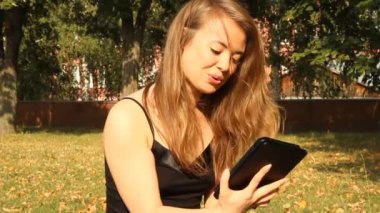 genç bir kız ile bir tablet bilgisayar bir parkta. Yaz