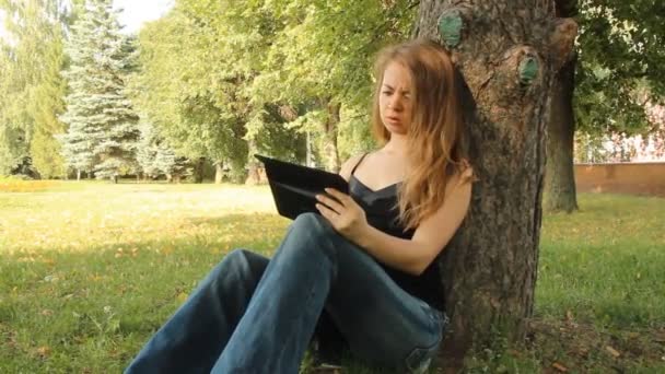 一个年轻的女孩在公园和一款平板电脑。夏天 — 图库视频影像